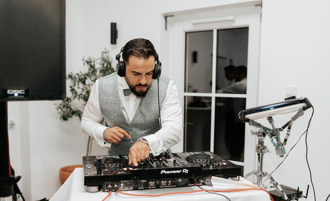 DJ im Home-Studio/weißem Raum, konzentriert am Setup.