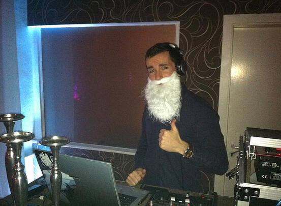 DJ am Mischpult in blauem Licht, moderner Screen im Hintergrund.