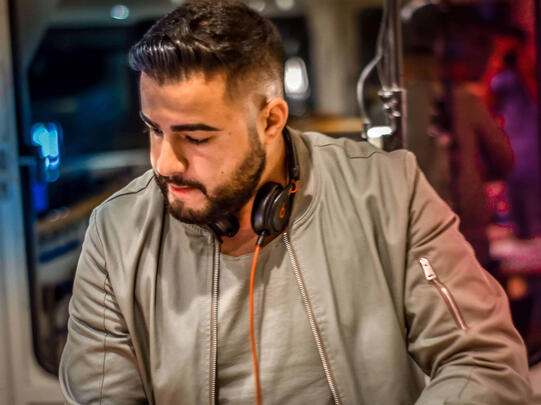 Close-up des DJs mit Kopfhörern am Hals, konzentrierter Blick.