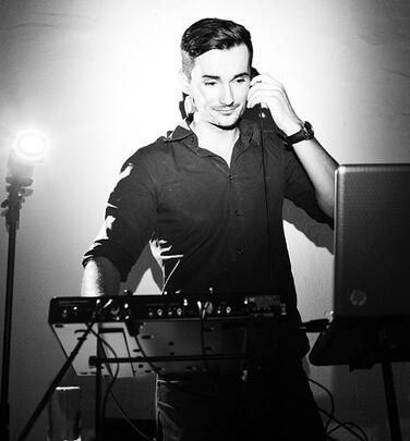 Schwarz-weiß Porträt am DJ-Pult, dramatisches Licht.