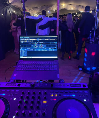 DJ-Pult mit Tellern/Fadern im Vordergrund, Bühne hinten.